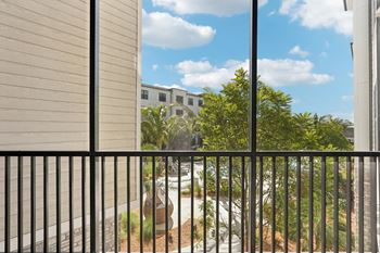 A view from a balcony looking out at a courtyard with a building in the background